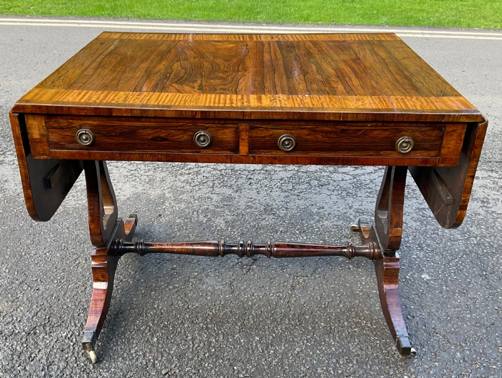 A Georgian walnut drop-leaf sofa table with crossbanded top inlay, two frieze drawers with brass ring handles, turned stretcher support, and splayed legs on castors. View VIII