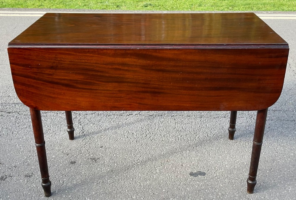 A Georgian mahogany Pembroke table featuring two drop-leaf sides, a single frieze drawer with brass handles, and four turned legs. View II