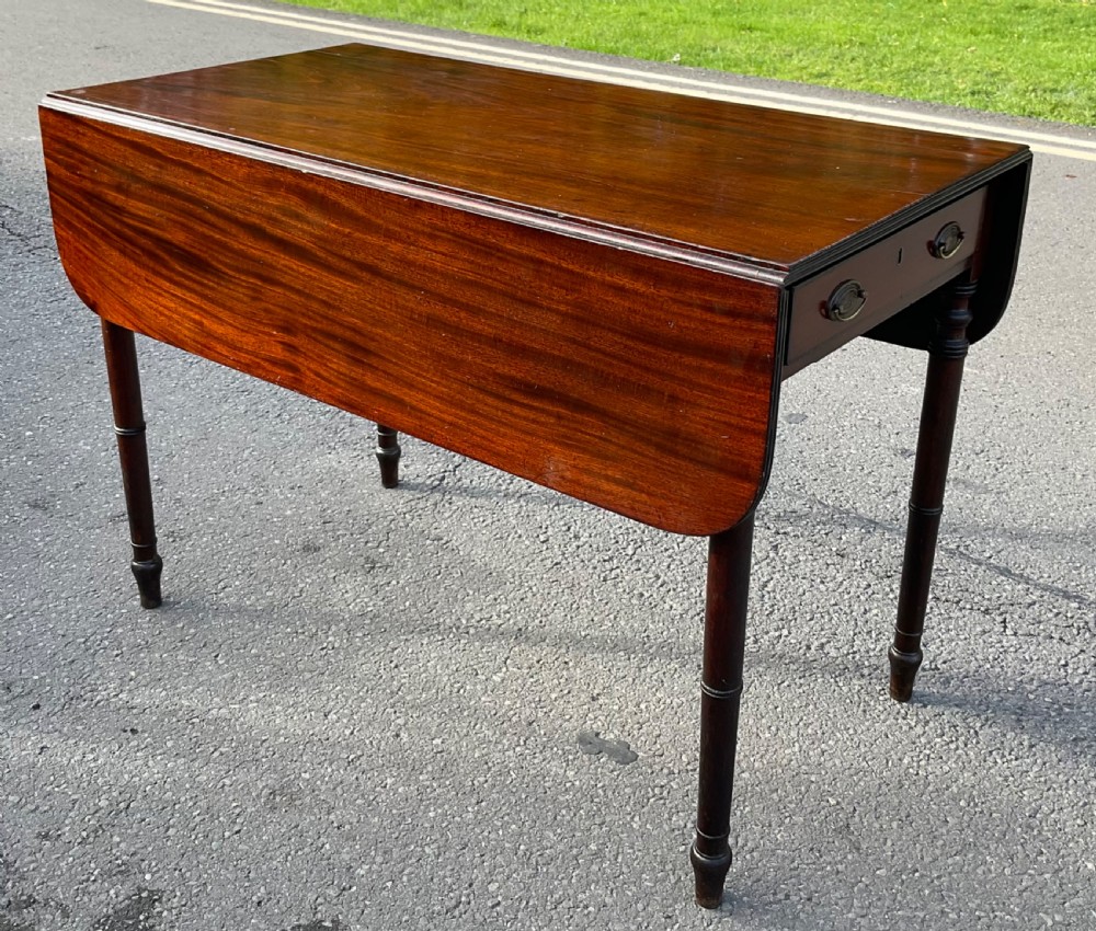 A Georgian mahogany Pembroke table featuring two drop-leaf sides, a single frieze drawer with brass handles, and four turned legs. View IV