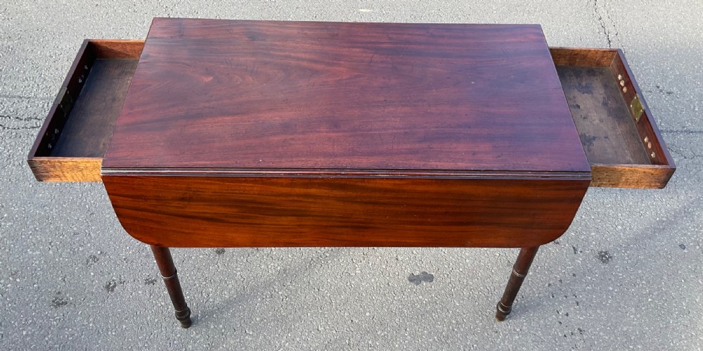 A Georgian mahogany Pembroke table featuring two drop-leaf sides, a single frieze drawer with brass handles, and four turned legs. View V