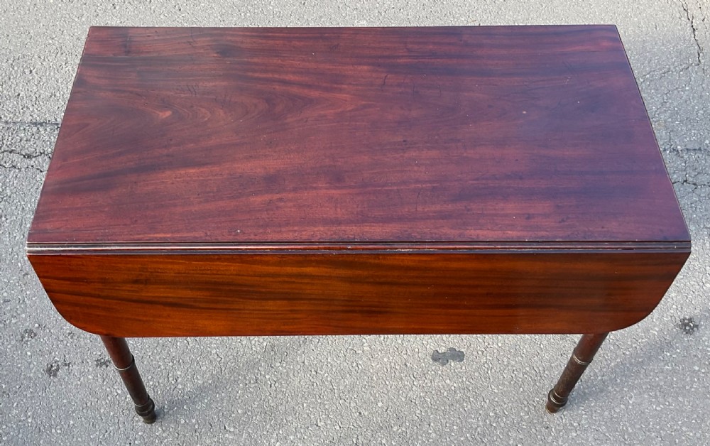 A Georgian mahogany Pembroke table featuring two drop-leaf sides, a single frieze drawer with brass handles, and four turned legs. View VI