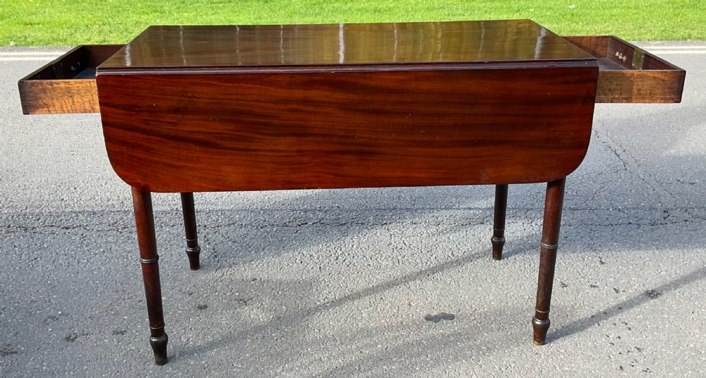 A Georgian mahogany Pembroke table featuring two drop-leaf sides, a single frieze drawer with brass handles, and four turned legs. View VII