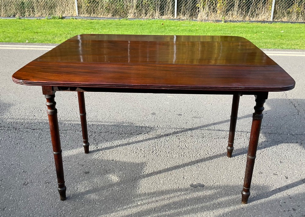 A Georgian mahogany Pembroke table featuring two drop-leaf sides, a single frieze drawer with brass handles, and four turned legs. View XII