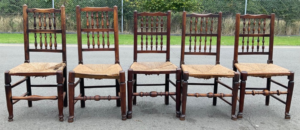 A set of five antique elm Lancashire spindleback dining chairs featuring double-tiered turned back spindles and woven rush seats. View II