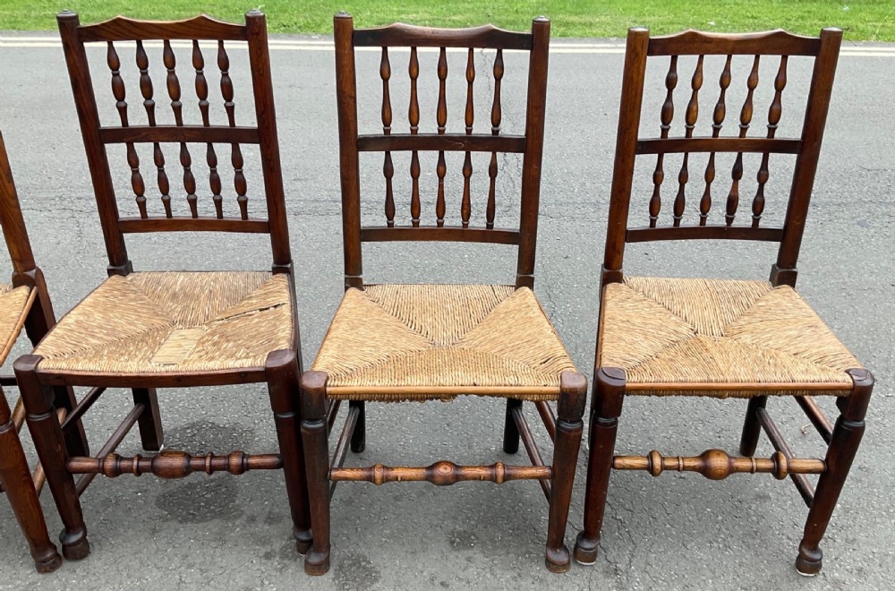 A set of five antique elm Lancashire spindleback dining chairs featuring double-tiered turned back spindles and woven rush seats. View IV