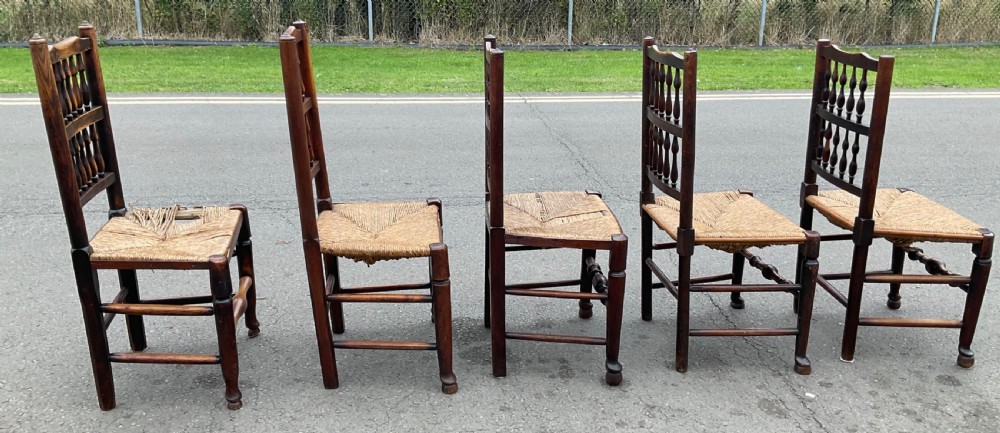 A set of five antique elm Lancashire spindleback dining chairs featuring double-tiered turned back spindles and woven rush seats. View VIII