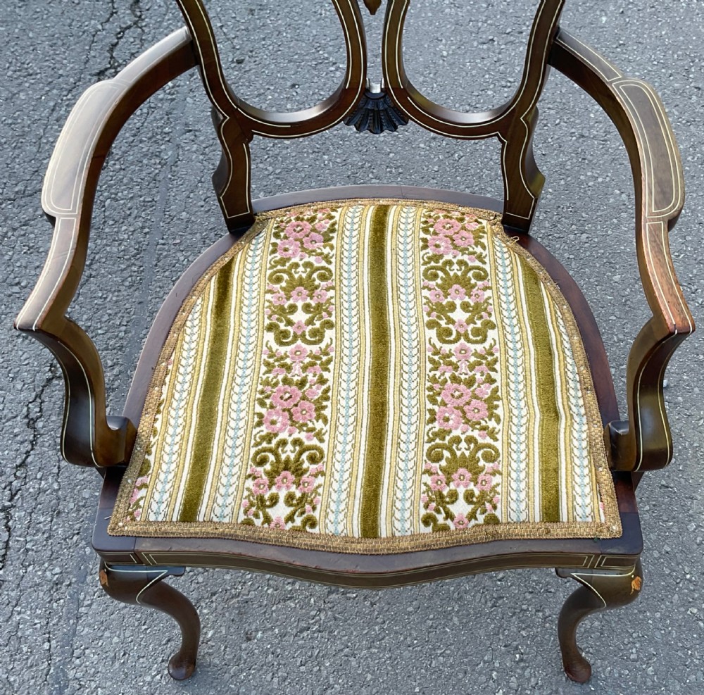 An Edwardian dark mahogany armchair with floral marquetry inlay on the splat back, cabriole front legs, and a patterned velvet upholstered seat. View VI