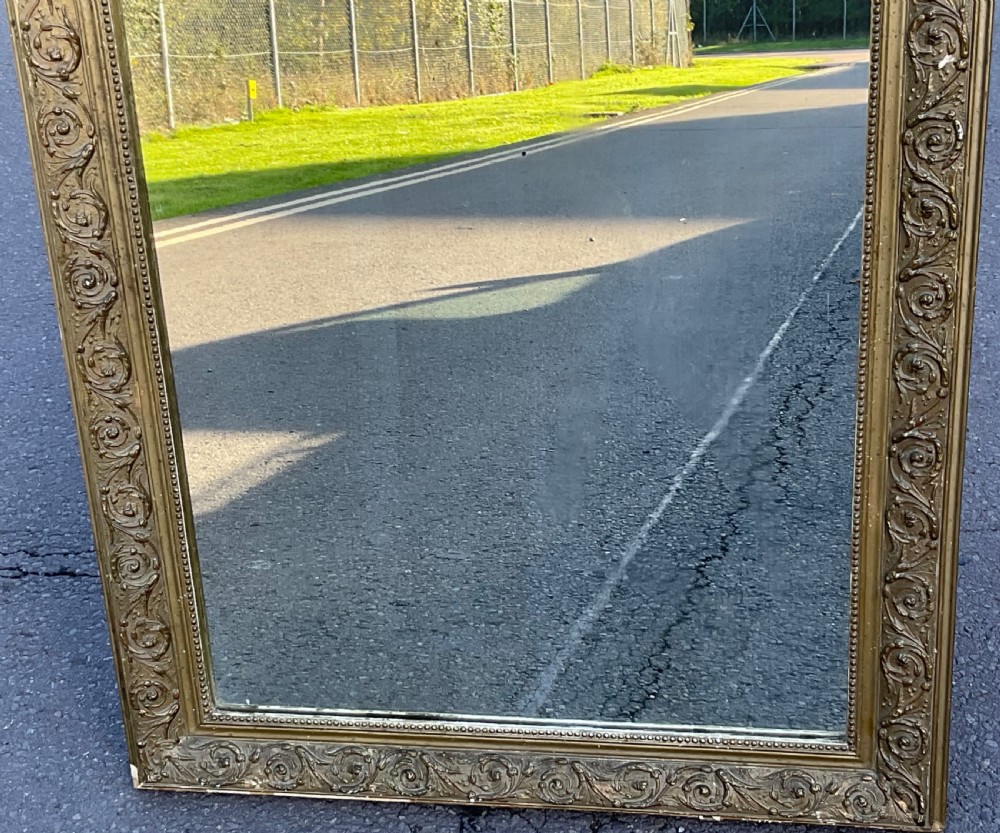 A rectangular Regency overmantel mirror featuring rounded upper corners, a beaded inner rim, and a floral foliage scroll motif on a gilded frame. View V