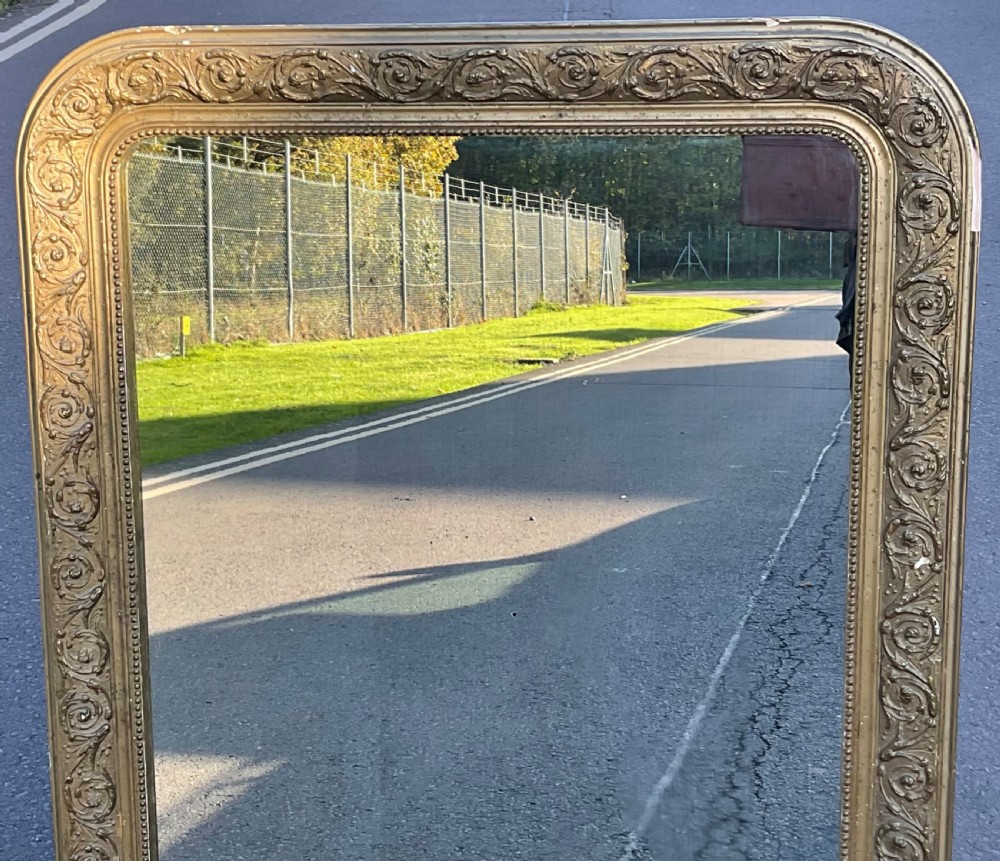 A rectangular Regency overmantel mirror featuring rounded upper corners, a beaded inner rim, and a floral foliage scroll motif on a gilded frame. View VII