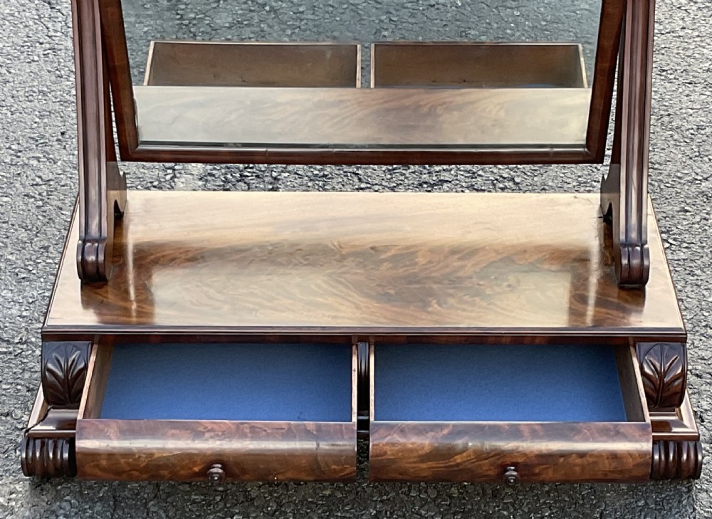 A mahogany toilet mirror featuring a rectangular swivelling glass frame supported by turned uprights on a plinth base with a frieze drawer and carved feet. View V