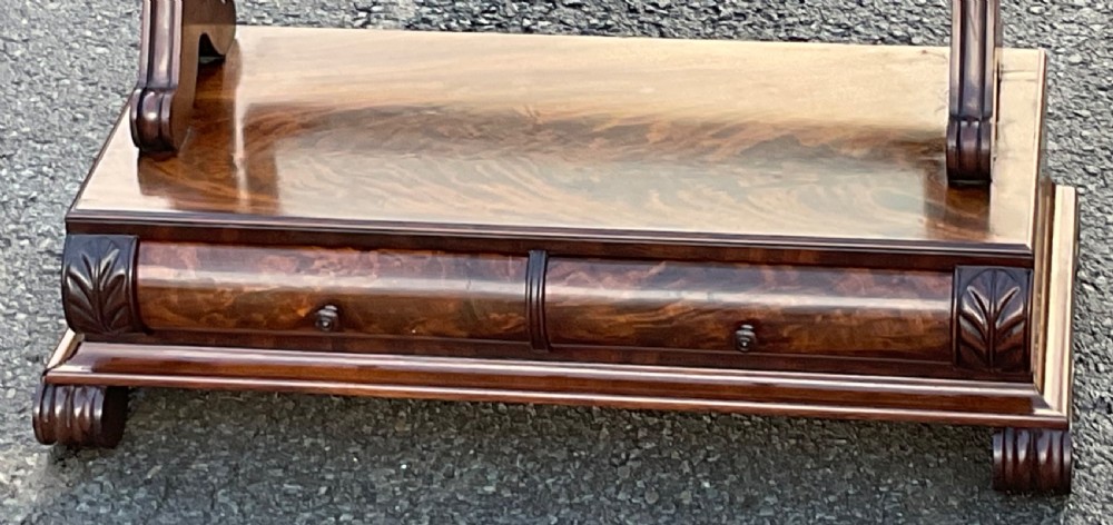 A mahogany toilet mirror featuring a rectangular swivelling glass frame supported by turned uprights on a plinth base with a frieze drawer and carved feet. View VI