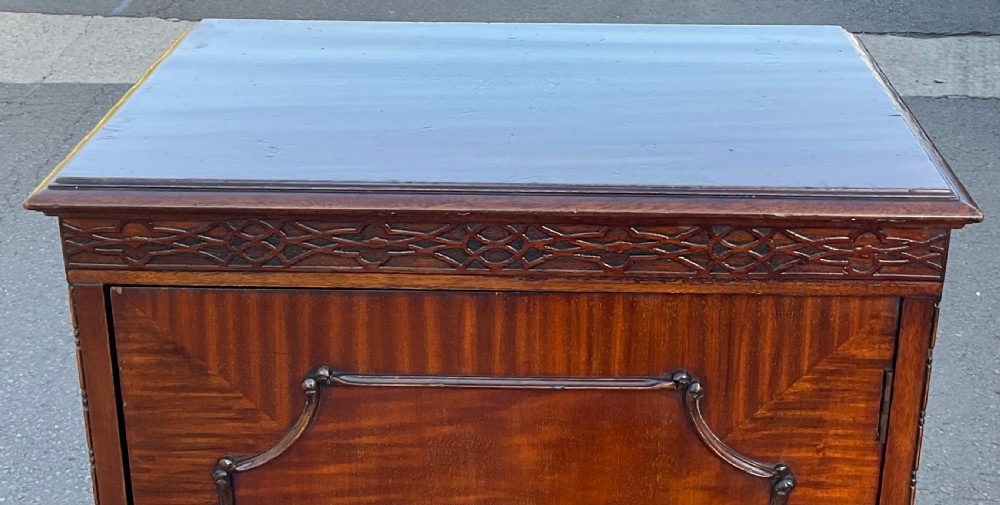An Edwardian mahogany music cabinet featuring a single door with flame mahogany veneering, top blind fretwork band, and cabriole legs on ball and claw feet. View V