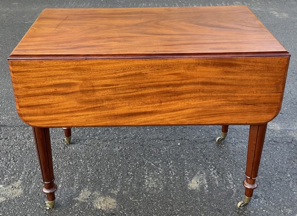 A Victorian mahogany Pembroke table featuring two drop leaves, a single frieze drawer with wooden knobs, turned reeded legs, and brass castors. View III