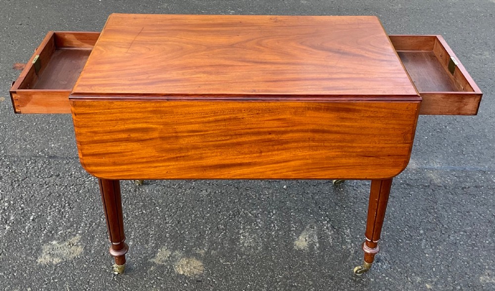 A Victorian mahogany Pembroke table featuring two drop leaves, a single frieze drawer with wooden knobs, turned reeded legs, and brass castors. View IV