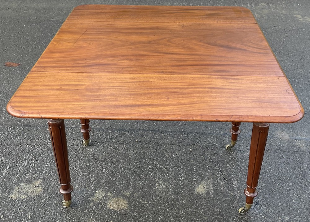 A Victorian mahogany Pembroke table featuring two drop leaves, a single frieze drawer with wooden knobs, turned reeded legs, and brass castors. View VII
