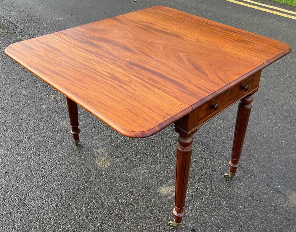 A Victorian mahogany Pembroke table featuring two drop leaves, a single frieze drawer with wooden knobs, turned reeded legs, and brass castors. View X
