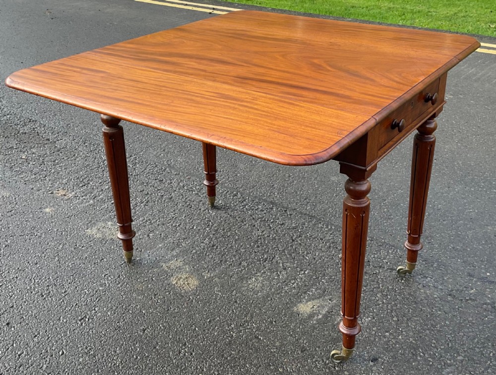A Victorian mahogany Pembroke table featuring two drop leaves, a single frieze drawer with wooden knobs, turned reeded legs, and brass castors. View XI