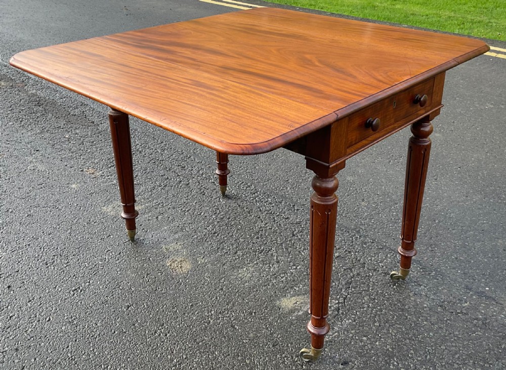 A Victorian mahogany Pembroke table featuring two drop leaves, a single frieze drawer with wooden knobs, turned reeded legs, and brass castors. View XII