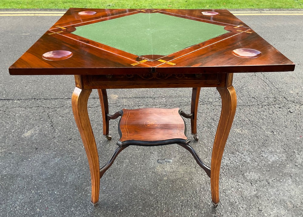 An Edwardian inlaid mahogany envelope card table featuring triangular fold-out top sections with marquetry urn motifs, a single frieze drawer, cabriole legs, and a shaped undertier. View VIII