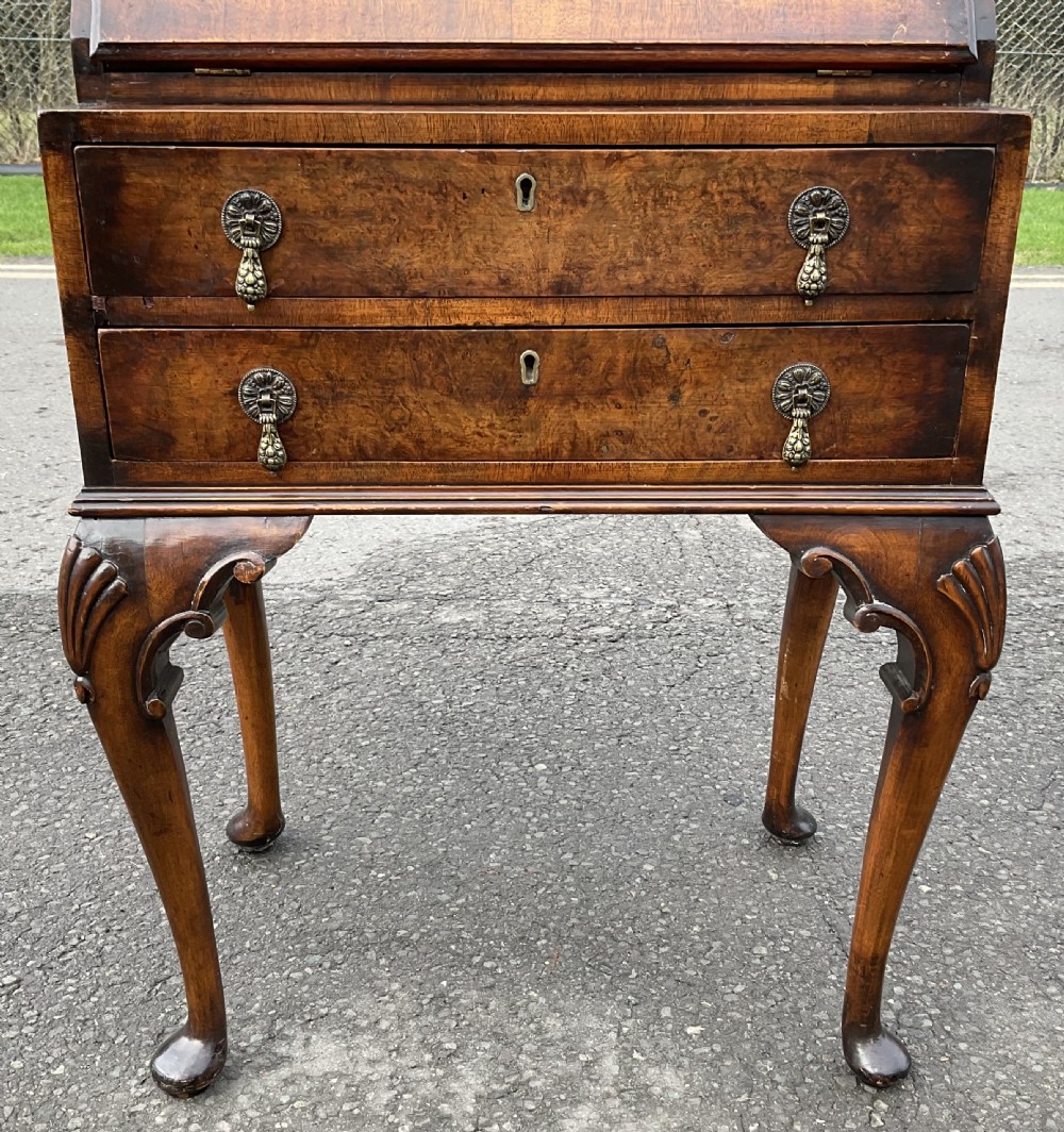A small Queen Anne style walnut writing bureau featuring a slant-front flap, two drawers with brass handles, and cabriole legs with pad feet. View II