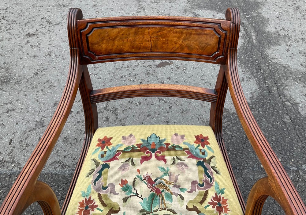 A Regency mahogany carver armchair featuring reeded scrolling arms, reeded curved legs, a tablet back rail, and a yellow needlepoint upholstered seat depicting floral and bird motifs. View III