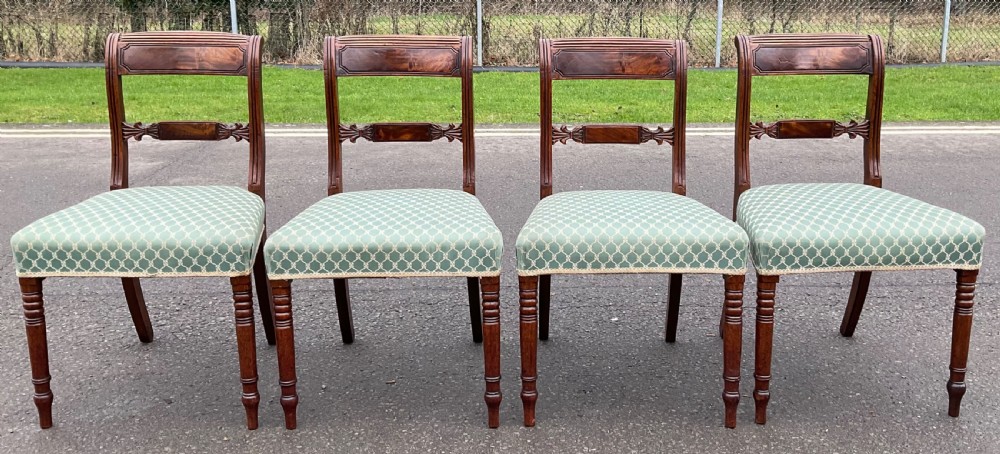 A set of four antique Georgian mahogany dining chairs with flame mahogany top rails, carved crossbars, turned front legs, and green pattern upholstered seats. View II
