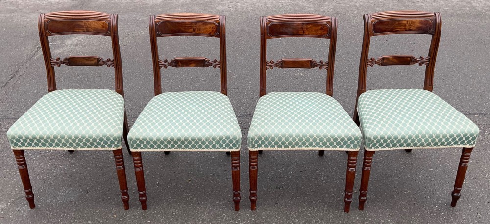 A set of four antique Georgian mahogany dining chairs with flame mahogany top rails, carved crossbars, turned front legs, and green pattern upholstered seats. View III