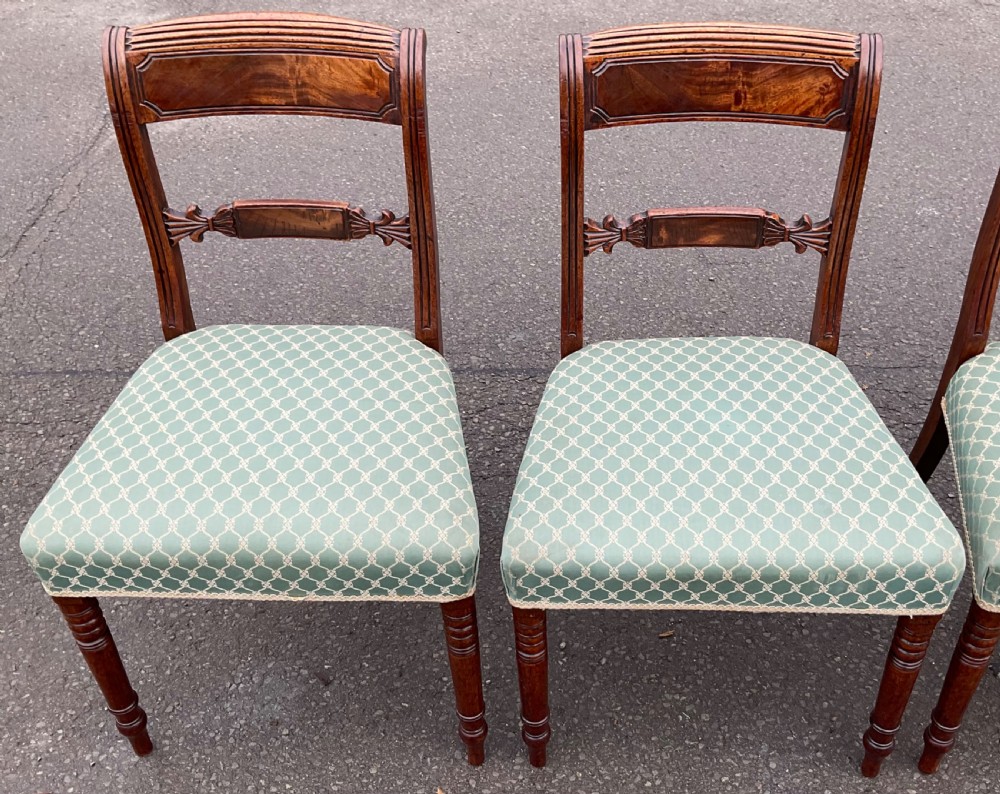 A set of four antique Georgian mahogany dining chairs with flame mahogany top rails, carved crossbars, turned front legs, and green pattern upholstered seats. View IV