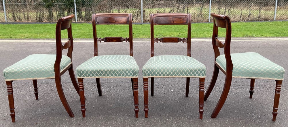 A set of four antique Georgian mahogany dining chairs with flame mahogany top rails, carved crossbars, turned front legs, and green pattern upholstered seats. View VI