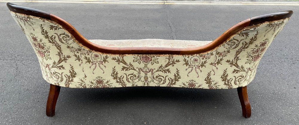 A Victorian upholstered settee featuring a carved mahogany frame with dual contoured backrests and olive green floral patterned fabric. View VIII