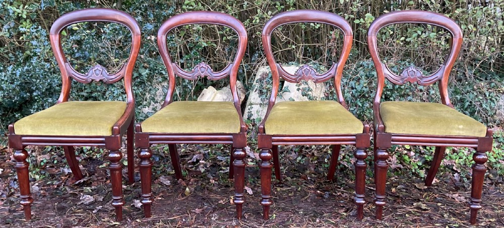 A set of four Victorian mahogany dining chairs featuring rounded balloon backs with carved central splats and olive green velvet upholstered seats. View II