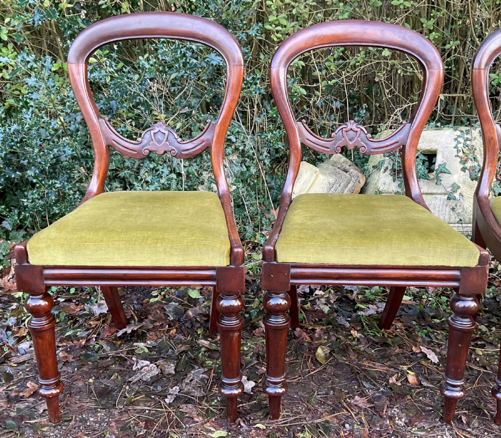 A set of four Victorian mahogany dining chairs featuring rounded balloon backs with carved central splats and olive green velvet upholstered seats. View III