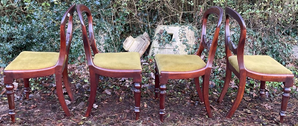A set of four Victorian mahogany dining chairs featuring rounded balloon backs with carved central splats and olive green velvet upholstered seats. View VII