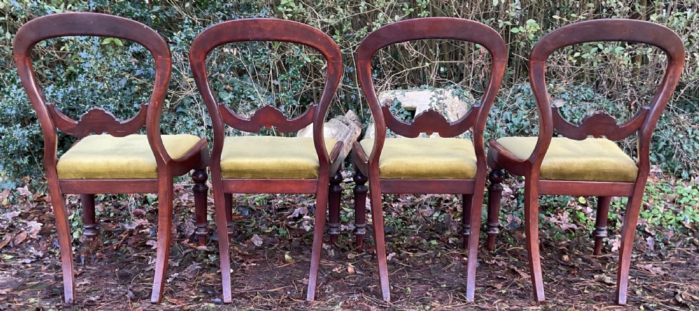 A set of four Victorian mahogany dining chairs featuring rounded balloon backs with carved central splats and olive green velvet upholstered seats. View VIII