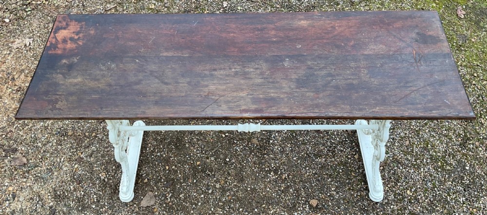 A long Victorian pub table featuring a dark wooden rectangular top supported by white painted decorative cast iron scrollwork legs and a central stretcher. View III
