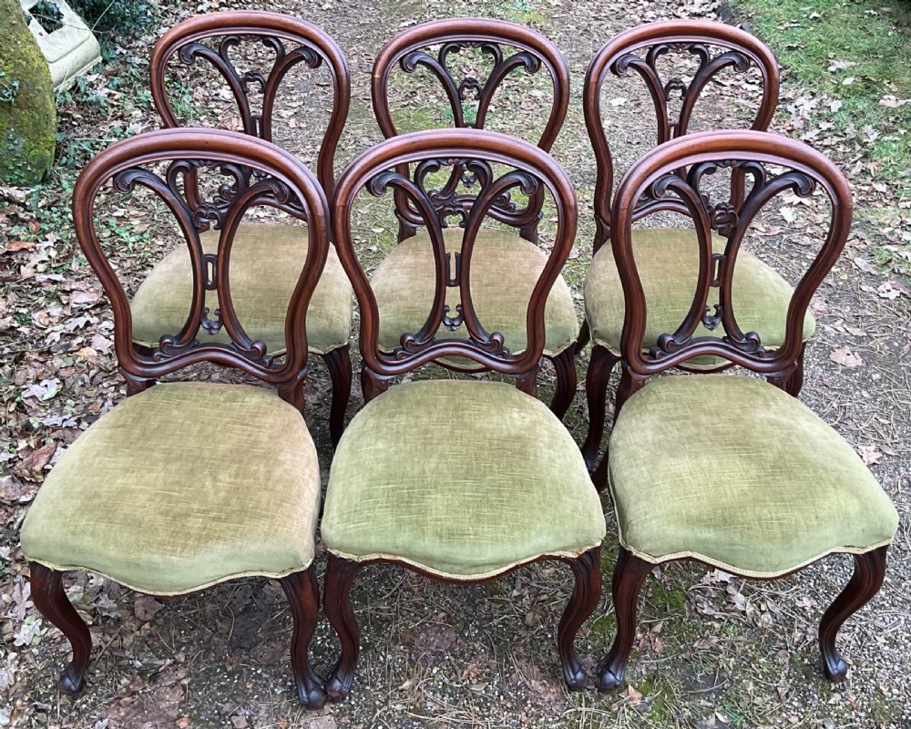 A set of six Victorian mahogany dining chairs featuring carved balloon back frames, cabriole front legs, and green velvet upholstered seats. View V