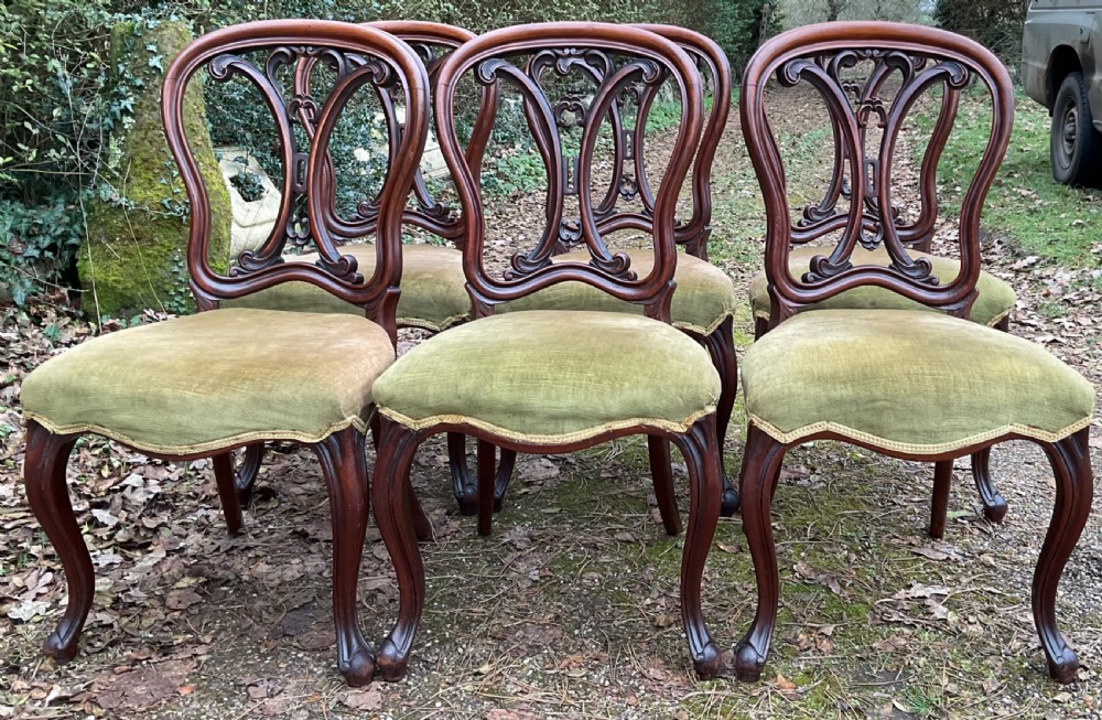 A set of six Victorian mahogany dining chairs featuring carved balloon back frames, cabriole front legs, and green velvet upholstered seats. View VI