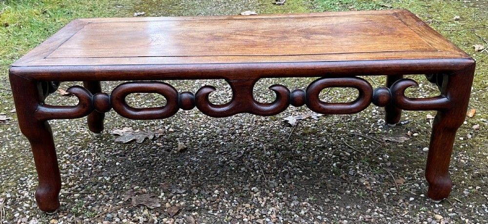 A low rectangular oriental hardwood coffee table featuring an intricately carved openwork apron and curved legs. View II
