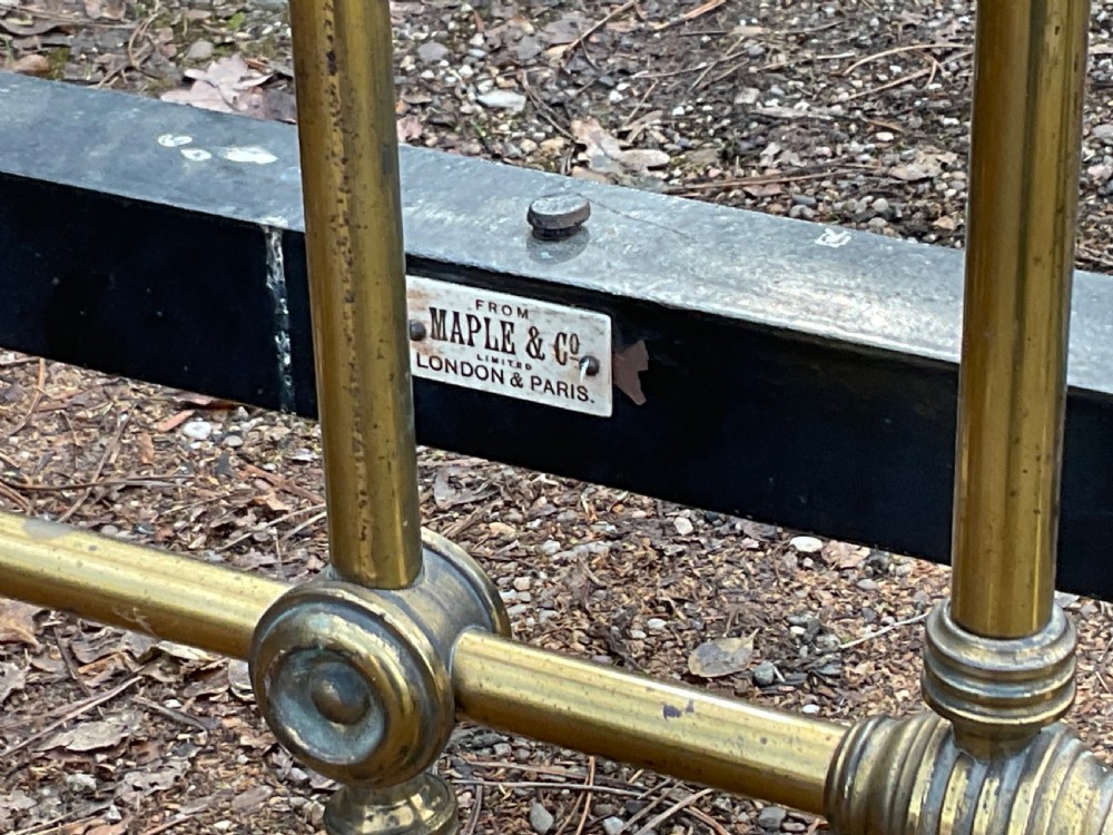 An antique brass five-foot bed frame featuring turned spindles, a central sunflower rosette motif on the footboard, spherical finials, and black iron side rails on castors. View IV