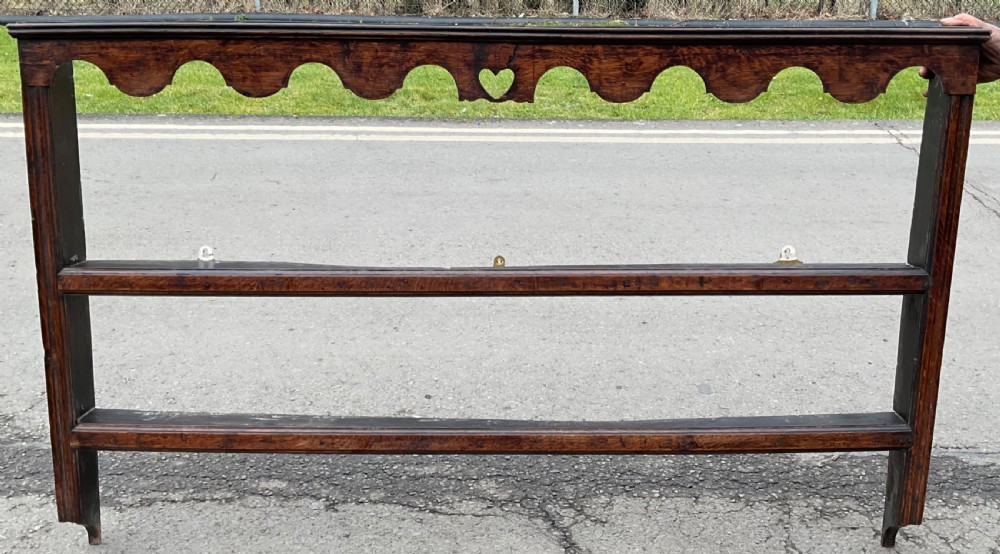 A dark oak wall shelf unit featuring two open tiers, a scalloped top frieze, and a central heart cutout motif. View III