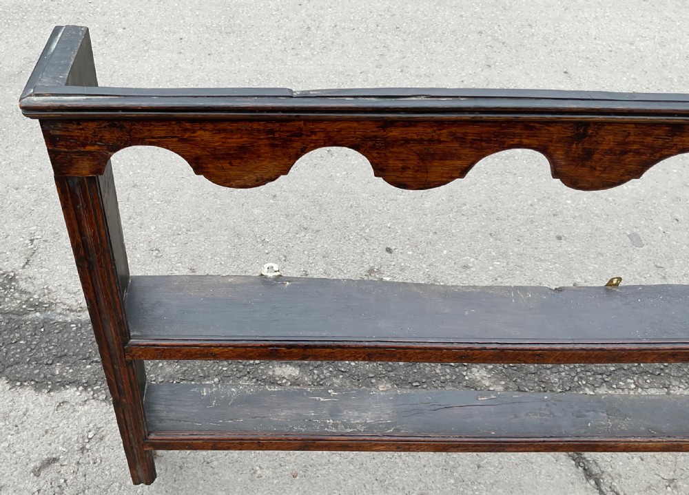 A dark oak wall shelf unit featuring two open tiers, a scalloped top frieze, and a central heart cutout motif. View IV