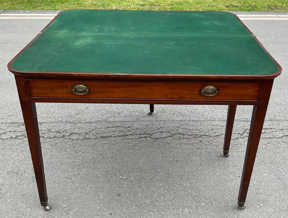 A Georgian mahogany card table featuring a rectangular fold-over top, a single long drawer with oval brass handles, tapered legs, and small brass castors. View VI