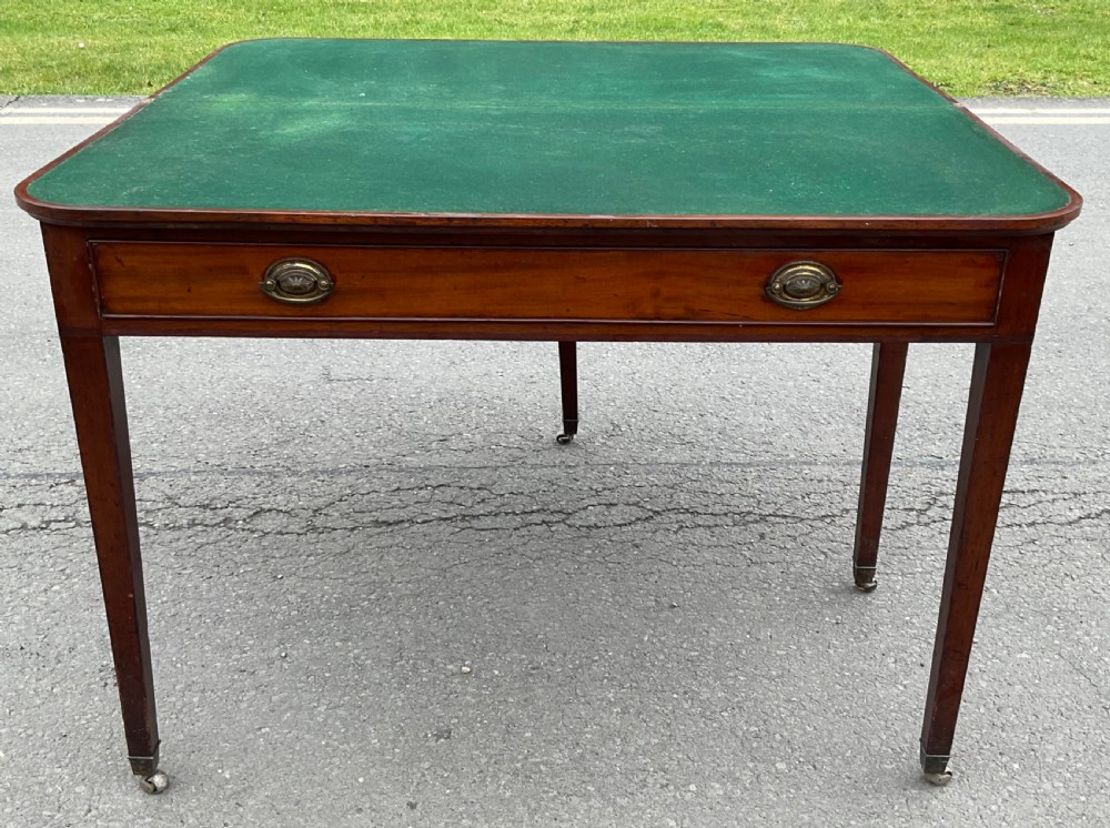 A Georgian mahogany card table featuring a rectangular fold-over top, a single long drawer with oval brass handles, tapered legs, and small brass castors. View VII