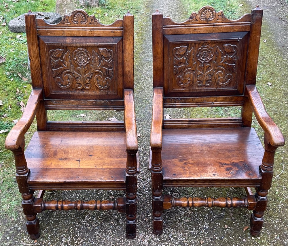 A pair of dark oak wainscot armchairs featuring carved floral back panels and turned legs. View II