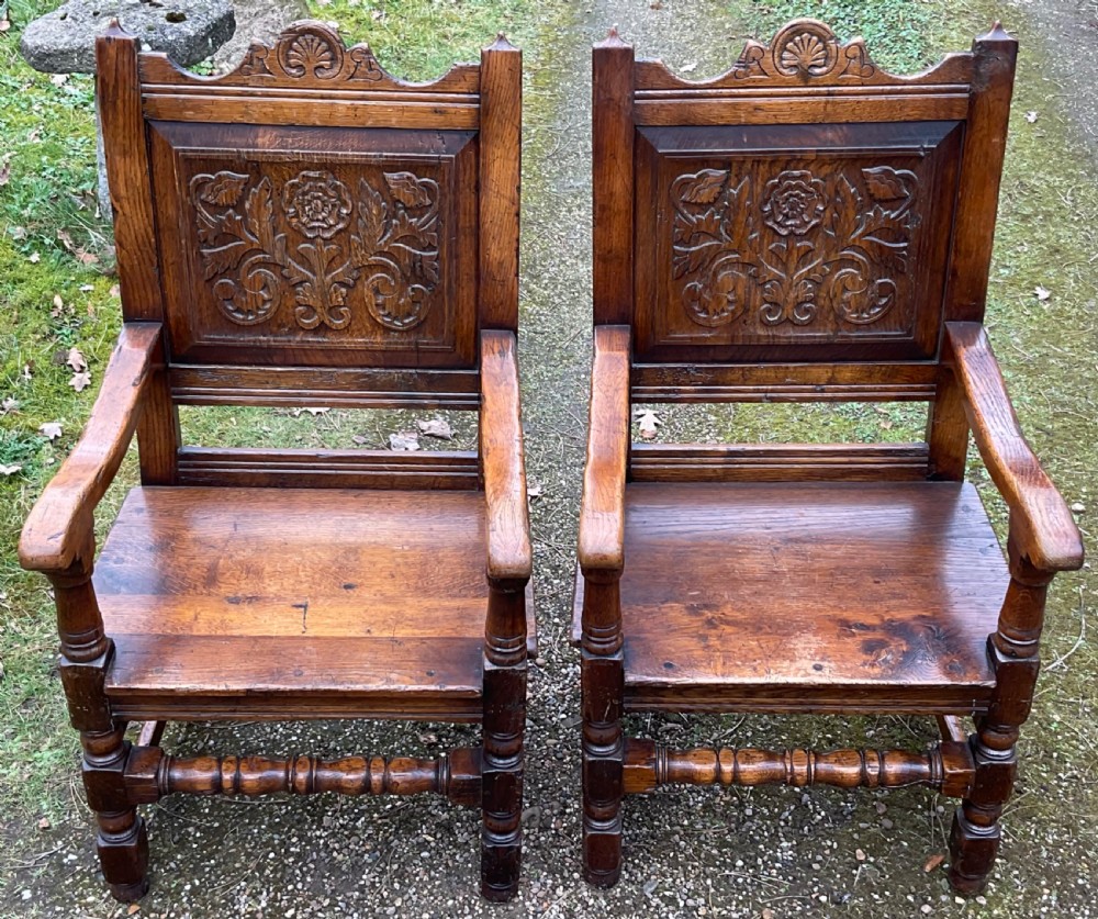 A pair of dark oak wainscot armchairs featuring carved floral back panels and turned legs. View III