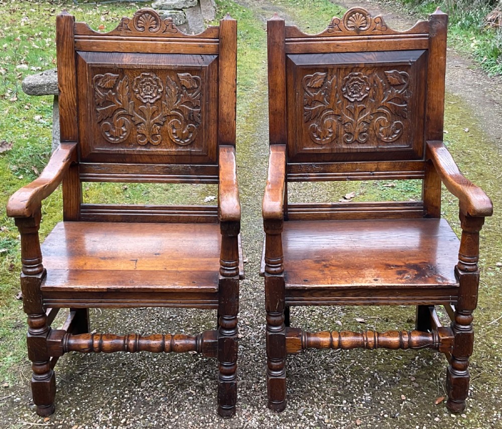 A pair of dark oak wainscot armchairs featuring carved floral back panels and turned legs. View IV