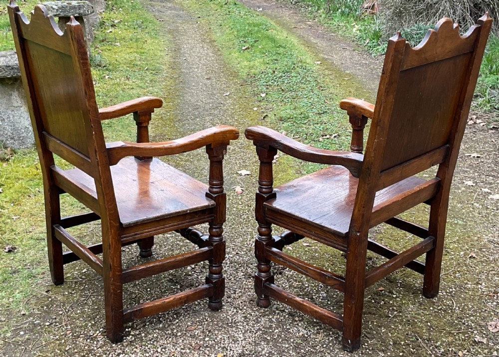 A pair of dark oak wainscot armchairs featuring carved floral back panels and turned legs. View VII