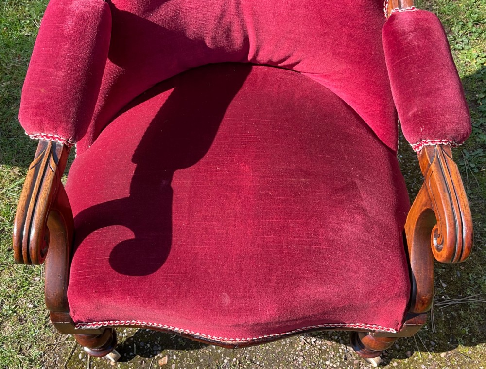 A William IV mahogany armchair upholstered in crimson red velvet with button-backed cushioning and turned front legs on castors. View IV