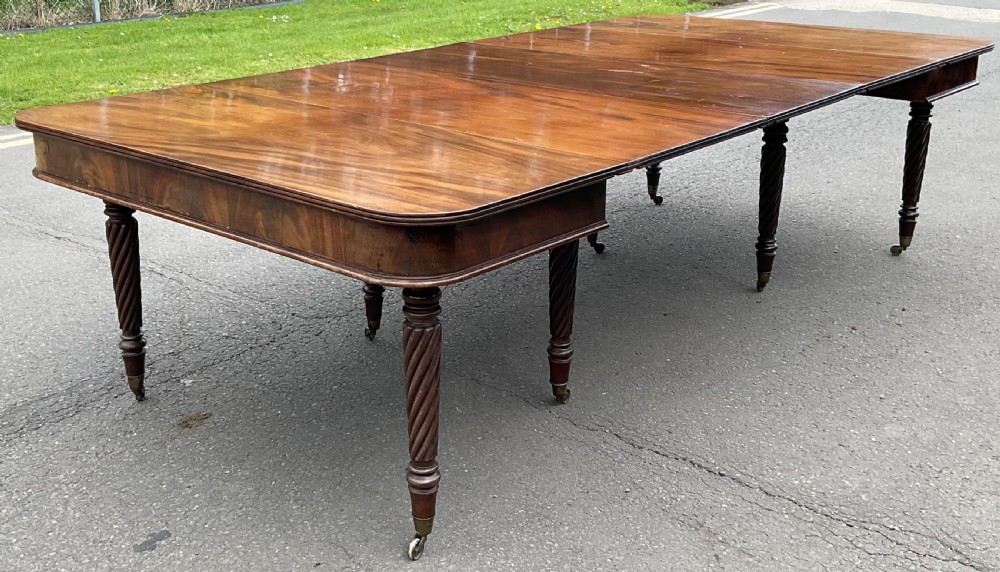 A large Regency mahogany extending dining table featuring spiral-turned legs fitted with brass castors.