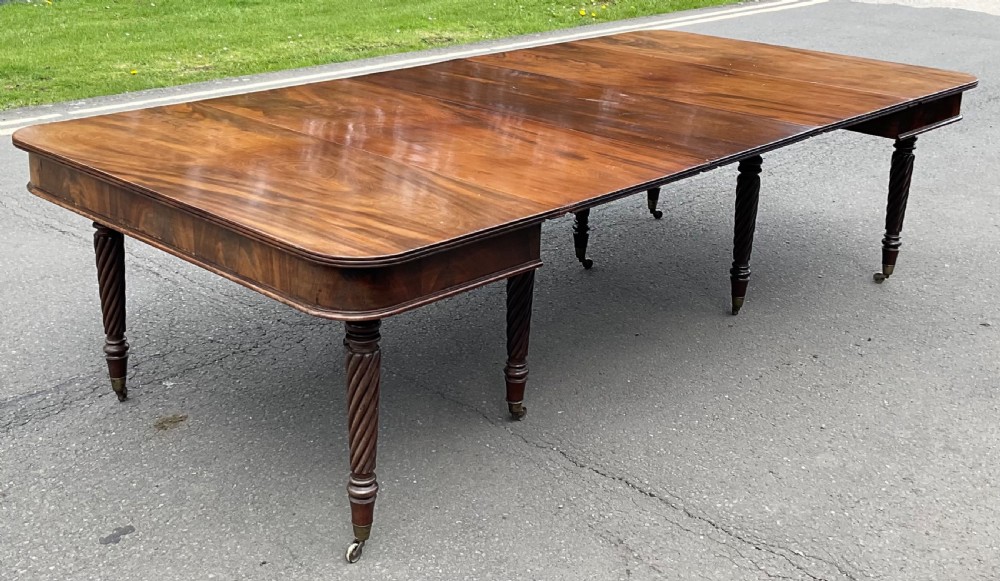 A large Regency mahogany extending dining table featuring spiral-turned legs fitted with brass castors. View II